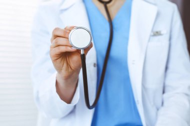 Bilinmeyen doktor kadın steteskop başı tutuyor, yakın plan. Doktor hastayı muayene etmeye ve yardım etmeye hazır. Sağlık hizmetleri, en iyi tedavi ve tıp konseptinde yardım ve sigorta