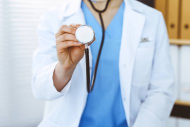Bilinmeyen doktor kadın steteskop başı tutuyor, yakın plan. Doktor hastayı muayene etmeye ve yardım etmeye hazır. Sağlık hizmetleri, en iyi tedavi ve tıp konseptinde yardım ve sigorta