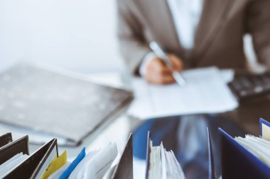 Muhasebeci kadın ya da finans müfettişi tarafından incelenmeyi bekleyen dosyalar. İş portresi. Denetim veya vergi kavramları