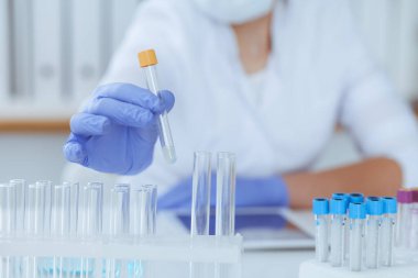 Koruyucu gözlüklü profesyonel kadın bilim adamının laboratuarda reaktörlerle deney yapması. Tıp ve araştırma konsepti