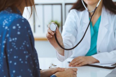 Elinde steteskop olan bir doktor. Doktor kadın hastasını muayene etmeye hazır..