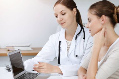 Doktor ve hasta dizüstü bilgisayar kullanırken oturup sağlık muayenesi sonuçlarını tartışıyor. Sağlık, ilaç ve iyi haber kavramları