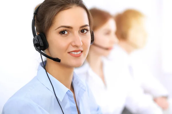 Bel het centrum. Focus op mooie zakelijke vrouw met behulp van headset in zonnig kantoor — Stockfoto