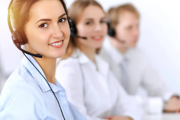 Bel het centrum. Focus op mooie zakelijke vrouw met behulp van headset in zonnig kantoor — Stockfoto