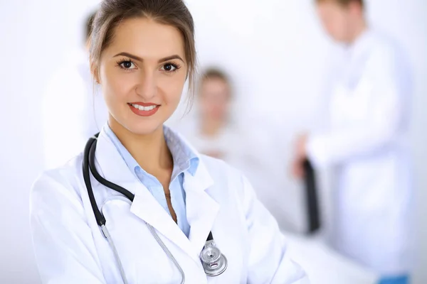 Vrouwelijke arts glimlachen op de achtergrond met patiënt in het bed en twee artsen — Stockfoto