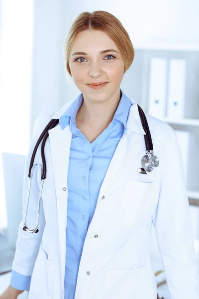 Junge Ärztin bei der Arbeit im Krankenhaus und blickt in die Kamera. Blaue Bluse des Therapeuten sieht gut aus. Medizin und Gesundheitskonzept — Stockfoto