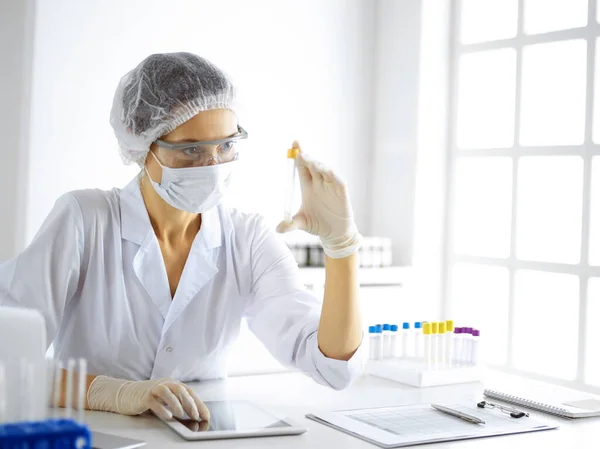 Científica profesional en gafas protectoras investigando tubo con reactivos en laboratorio. Conceptos de medicina e investigación — Foto de Stock