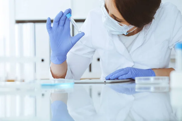 Profi női tudós közelkép védőszemüvegben kísérletezik reagensekkel a laboratóriumban. Orvosi és kutatási koncepció — Stock Fotó