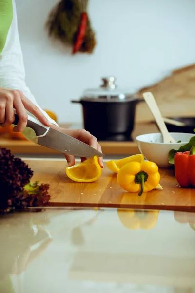Mãos humanas desconhecidas a cozinhar na cozinha. Mulher cortando pimentão amarelo. Refeição saudável e conceito de comida vegetariana — Fotografia de Stock