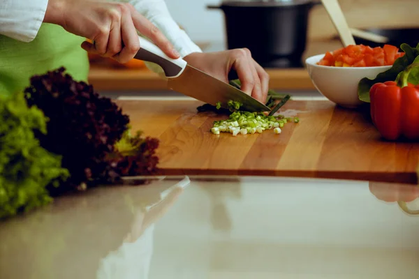 Manos humanas desconocidas cocinando en la cocina. Mujer cortando cebolla verde. Comida saludable y concepto de comida vegetariana —  Fotos de Stock