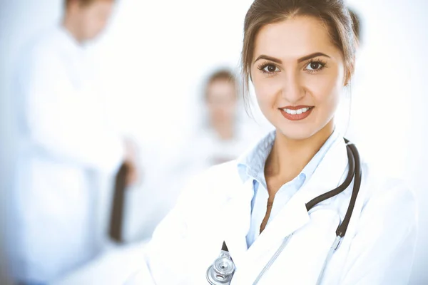 Doctora sonriendo en el fondo con paciente en la cama y dos doctores — Foto de Stock