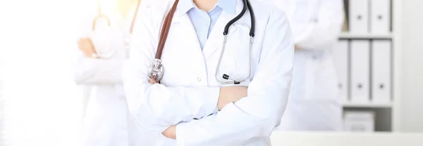 Unknown woman-doctor standing straight with arms crossed in clinic, close-up. Medical team ready to stop coronavirus pandemic. Medicine concept — Stock Photo, Image