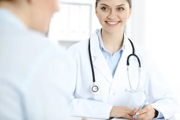 Amigável sorridente médico e paciente sentado à mesa — Fotografia de Stock