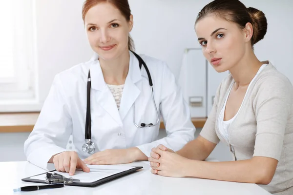 Médico y paciente sentado y discutiendo resultados de exámenes de salud en clínica soleada — Foto de Stock