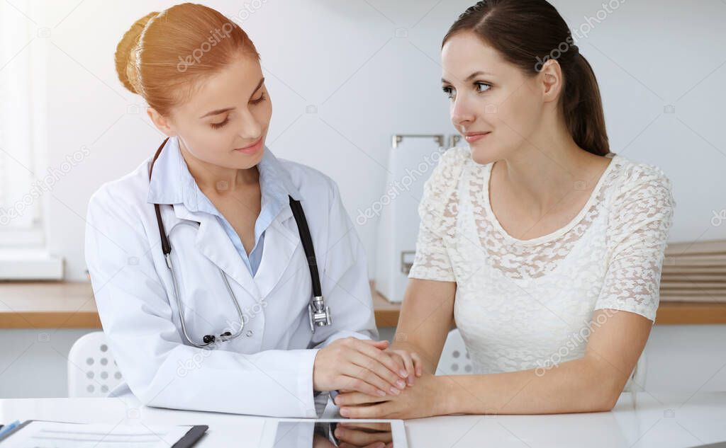 Woman-doctor reassuring her female patient while sitting at the desk. Medicine concept