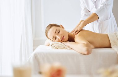 Güzel bir kadın kapalı gözlerle sırt masajından hoşlanıyor. Spa tedavisi kavramı