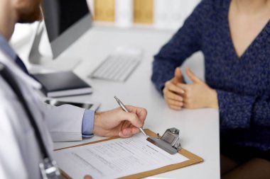 Bilinmeyen kızıl sakallı doktor ve hasta kadın güneşli klinikte otururken sağlık muayenesini tartışıyorlar. Tıp konsepti