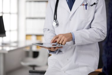 Klinikte tablet bilgisayar kullanan erkek doktor, yakın plan. Hastanede mükemmel bir tıbbi hizmet. Tıp ve sağlık hizmetleri kavramı