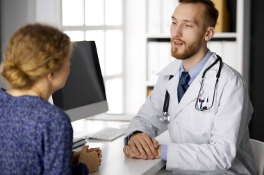 Bilinmeyen kızıl sakallı doktor ve hasta kadın güneşli klinikte otururken sağlık muayenesini tartışıyorlar. Tıp konsepti