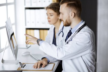 Kızıl sakallı doktor ve bayan meslektaşı klinikte çalışırken güncel hastalık terapisini tartışıyorlar. Tıpta takım çalışması