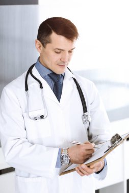 Doktor, ilaç kayıtlarını doldurmak için pano kullanıyor. Klinikte mükemmel bir tıbbi hizmet. Hastanede çalışan bir doktor. Tıp ve sağlık hizmetleri kavramları