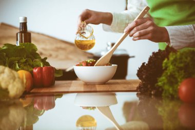 Mutfakta pişen bilinmeyen insan elleri. Kadın sebze salatasıyla meşgul. Sağlıklı yemek ve vejetaryen gıda konsepti.