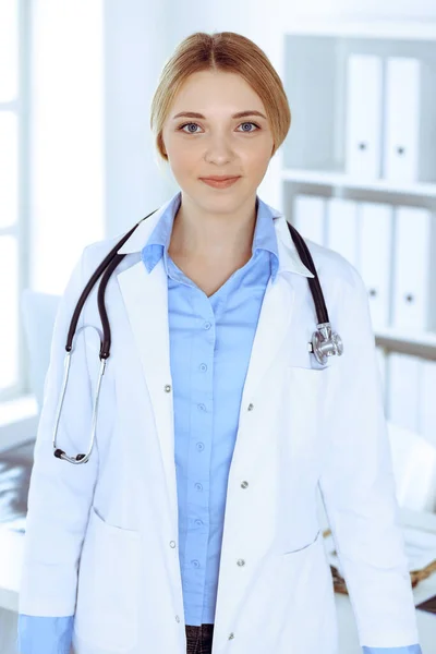 Junge Ärztin bei der Arbeit im Krankenhaus und blickt in die Kamera. Blaue Bluse des Therapeuten sieht gut aus. Medizin und Gesundheitskonzept — Stockfoto