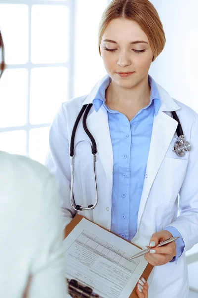 Fiatal doktornő és páciens a kórházi orvosi vizsgálaton. A terapeuta kék színű blúza jól néz ki. Orvosi és egészségügyi koncepció — Stock Fotó