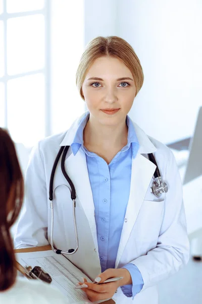 病院の診察室で若い女性医師と患者。セラピストの青い色のブラウスはよく見えます。医学と医療の概念 — ストック写真