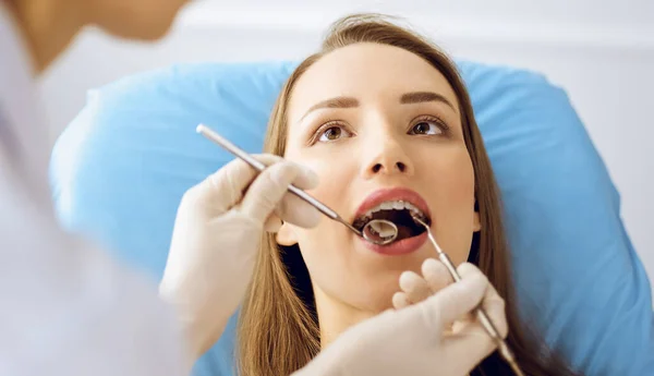 Smiling young woman with orthodontic brackets examined by dentist at dental clinic — Stock Photo, Image