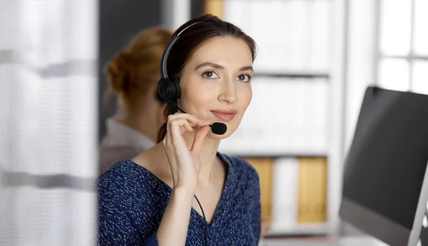 Amable mujer de negocios asiática o latinoamericana hablando por auriculares en la oficina. Centro de llamadas y grupo de personas diversas en los negocios —  Fotos de Stock