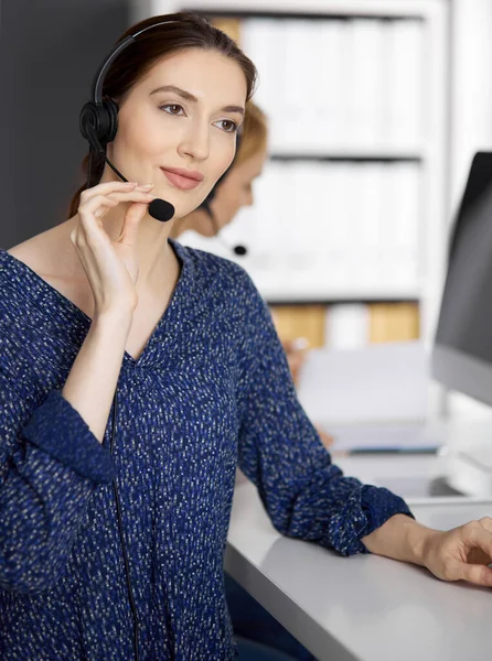 Amicale femme d'affaires asiatique ou latino-américaine parlant par casque au bureau. Centre d'appels et divers groupes de personnes en affaires — Photo