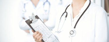 Bilinmeyen kadın-doktor klinikteki ilaç geçmişi kaydıyla ayakta duruyor, yakın plan. Tıp konsepti