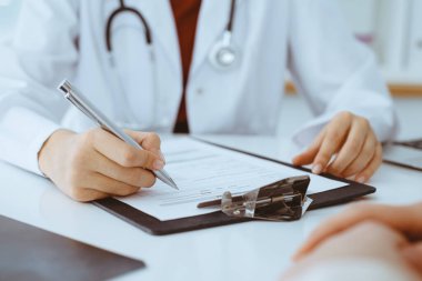 Bilinmeyen kadın-doktor hastaya danışmanlık yaparken başvuru formu dolduruyor. Tıp konsepti