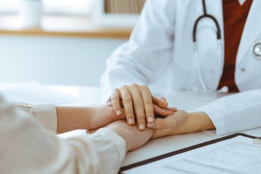 Kadın hastasına güvence veren kimliği belirsiz kadın doktorun elleri, yakın plan. Tıp konsepti