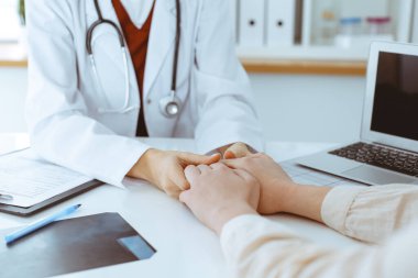 Kadın hastasına güvence veren kimliği belirsiz kadın doktorun elleri, yakın plan. Tıp konsepti