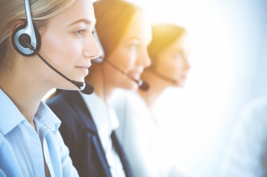 Kulaklıklı, güler yüzlü iş kadını müşterilere danışıyor. Sunny Office 'de çalışan çeşitli telefon operatörleri. Çağrı merkezi ve iş adamları kavramı.