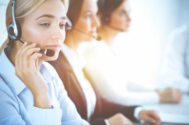 Kulaklıklı, güler yüzlü iş kadını müşterilere danışıyor. Sunny Office 'de çalışan çeşitli telefon operatörleri. Çağrı merkezi ve iş adamları kavramı.