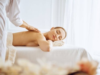Güzel bir kadın kapalı gözlerle sırt masajından hoşlanıyor. Spa tedavisi kavramı