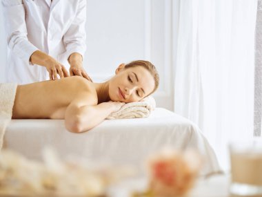 Güzel bir kadın kapalı gözlerle sırt masajından hoşlanıyor. Spa tedavisi kavramı
