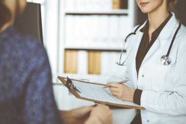 Doktor ve hasta klinikte otururken sağlık muayenesini tartışıyorlar. Hastanede mükemmel bir tıbbi hizmet.