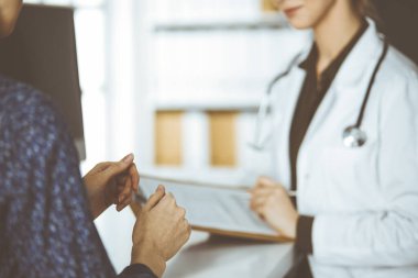 Doktor ve hasta klinikte otururken sağlık muayenesini tartışıyorlar. Hastanede mükemmel bir tıbbi hizmet.