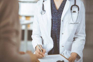 Doktor ve hasta klinikte otururken sağlık muayenesini tartışıyorlar. Hastanede mükemmel bir tıbbi hizmet.