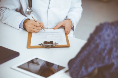 Bilinmeyen kızıl sakallı doktor ve hasta kadın güneşli klinikte otururken sağlık muayenesini tartışıyorlar. Tıp konsepti