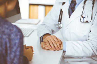 Dost canlısı kızıl sakallı doktor, kadın hastasına güvence veriyor, yakın plan. Tıp etiği ve güven kavramı, tıp teması