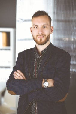 Kızıl sakallı, dost canlısı yetişkin iş adamı kameraya bakıyor. Güneşli ofiste iş vesikalığı ya da portre
