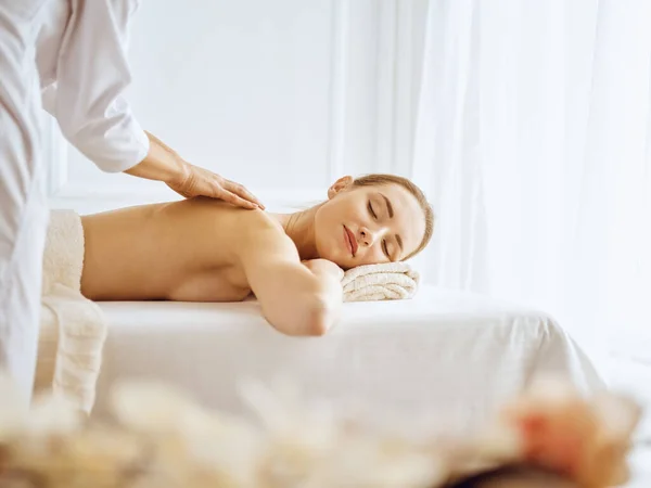 Hermosa mujer disfrutando de masaje de espalda con los ojos cerrados. Concepto de tratamiento Spa — Foto de Stock