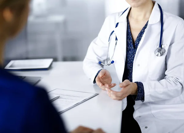 Bilinmeyen kadın-doktor, klinikteki dolapta birlikte otururken hastasıyla teşhisi hakkında konuşuyor. İşyerindeki doktor, yakın plan. Mükemmel bir tıbbi hizmet.