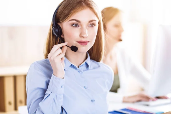 Toned portrait of call center operator at work. Group of people in a headset ready to help customers. Business concept