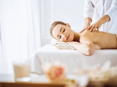 Güzel bir kadın kapalı gözlerle sırt masajından hoşlanıyor. Spa tedavisi kavramı.